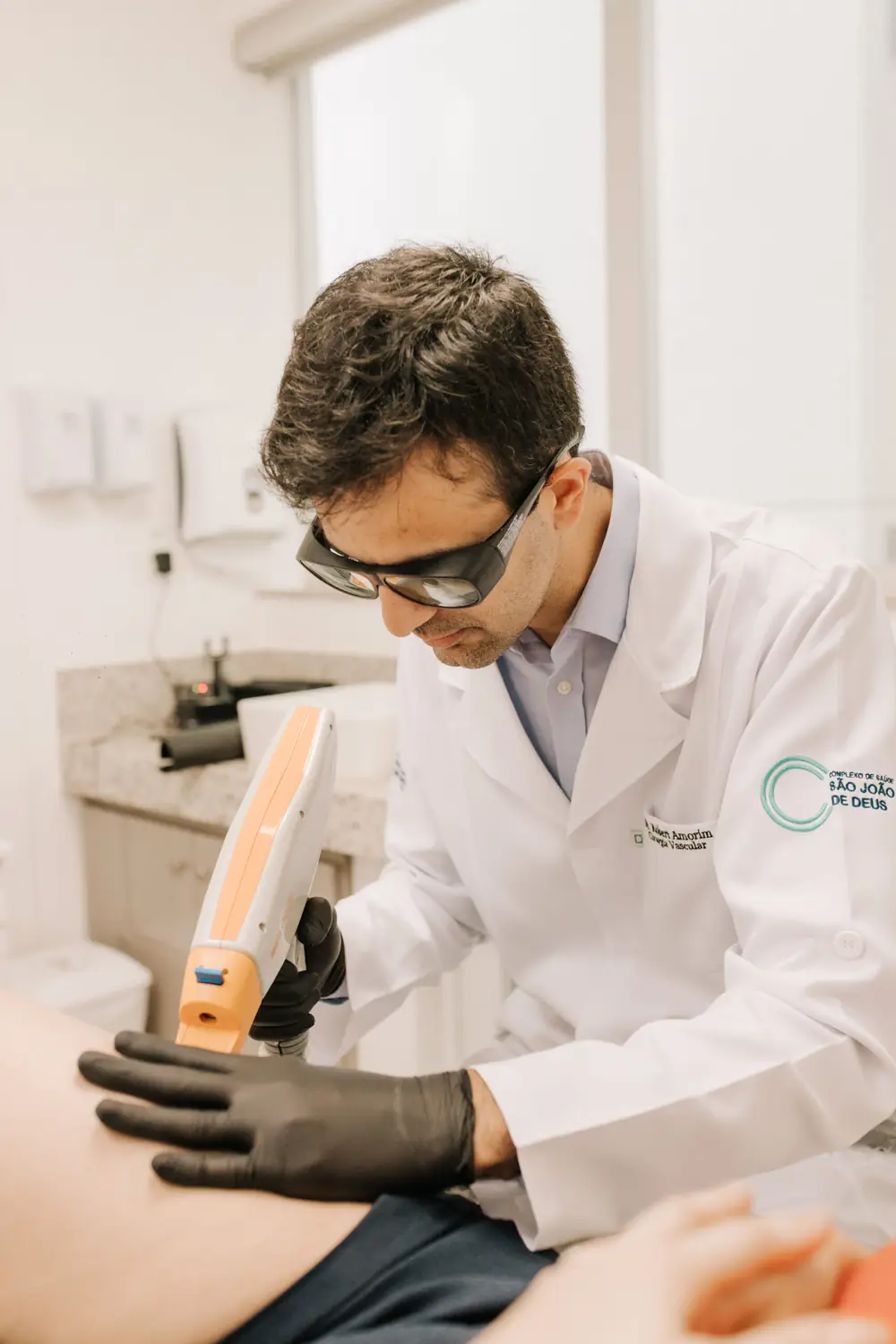 Médico aplicando laser na perna do paciente