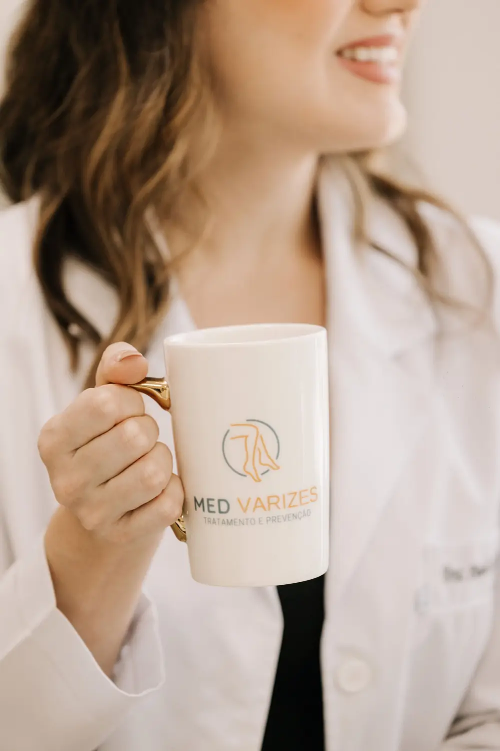 Médica da Med Varizes sorrindo com a caneca da clínica
